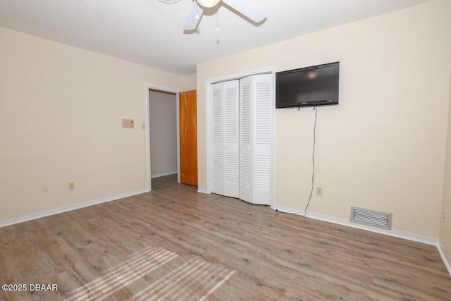 unfurnished bedroom featuring ceiling fan, a closet, and light wood-type flooring