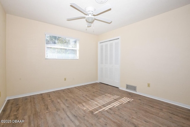 unfurnished bedroom with wood-type flooring, ceiling fan, and a closet