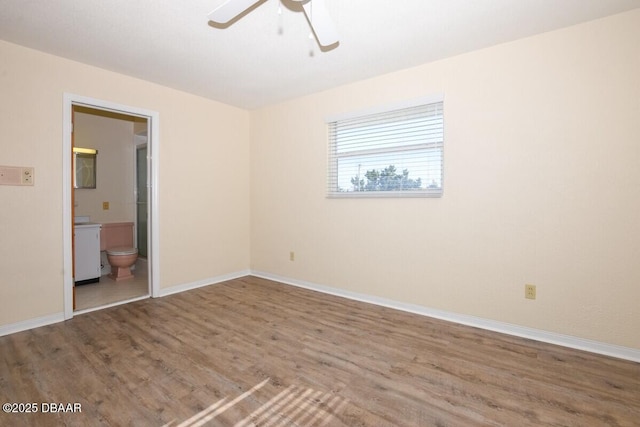 unfurnished bedroom with ceiling fan, ensuite bathroom, and hardwood / wood-style floors