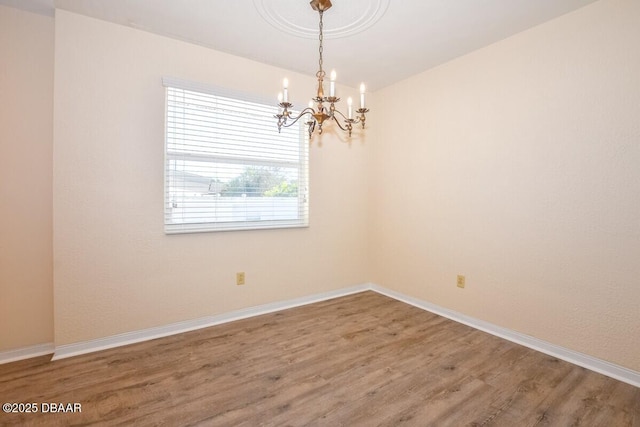 empty room with hardwood / wood-style flooring and a chandelier