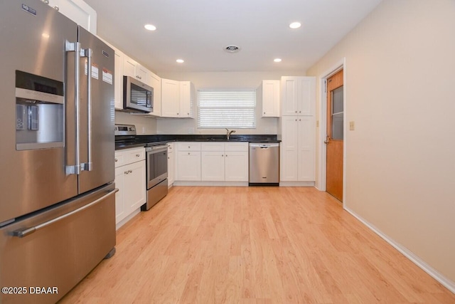 kitchen with white cabinetry, stainless steel appliances, sink, and light wood-type flooring