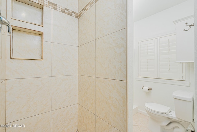 bathroom with tile patterned floors, toilet, and tiled shower