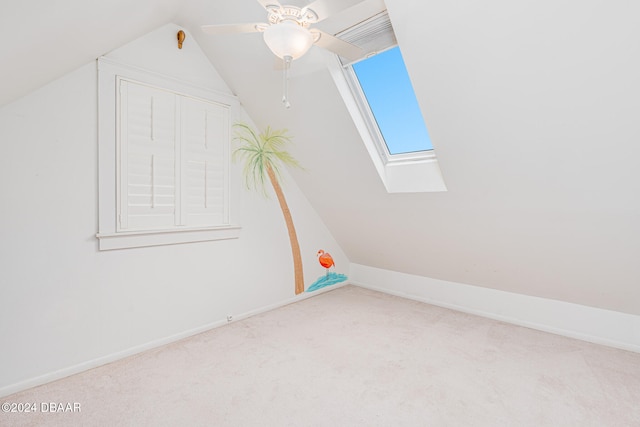 interior space featuring lofted ceiling with skylight, ceiling fan, and light colored carpet