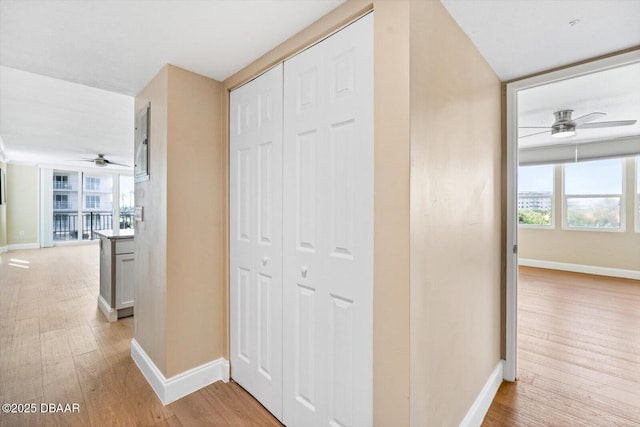 hallway featuring baseboards and light wood finished floors