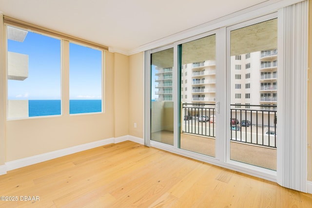 spare room featuring wood finished floors, baseboards, and a water view