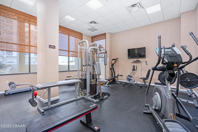 gym with visible vents, a paneled ceiling, and baseboards