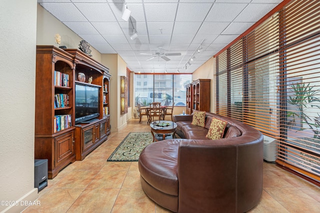 living area with a drop ceiling, rail lighting, light tile patterned floors, and ceiling fan