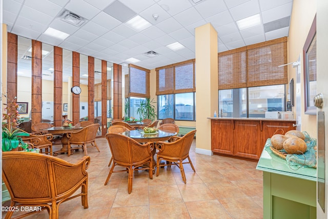 dining area featuring light tile patterned floors, visible vents, and a drop ceiling