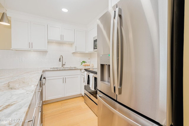 kitchen featuring light wood-style flooring, white cabinetry, stainless steel appliances, and a sink