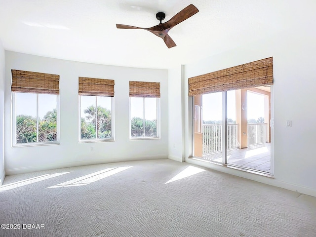 empty room featuring light carpet, plenty of natural light, baseboards, and ceiling fan