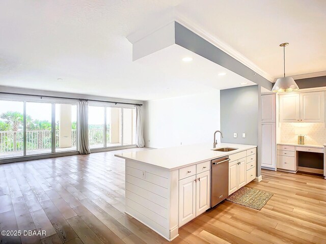 kitchen with a sink, open floor plan, light wood finished floors, dishwasher, and light countertops