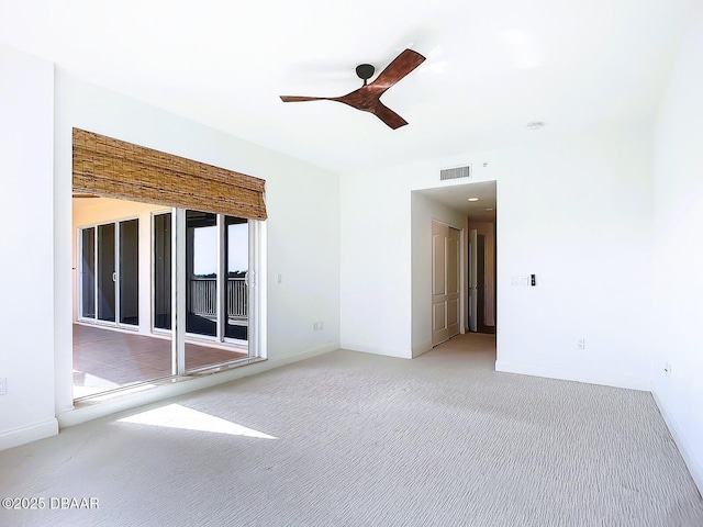 empty room featuring visible vents, a ceiling fan, and carpet floors