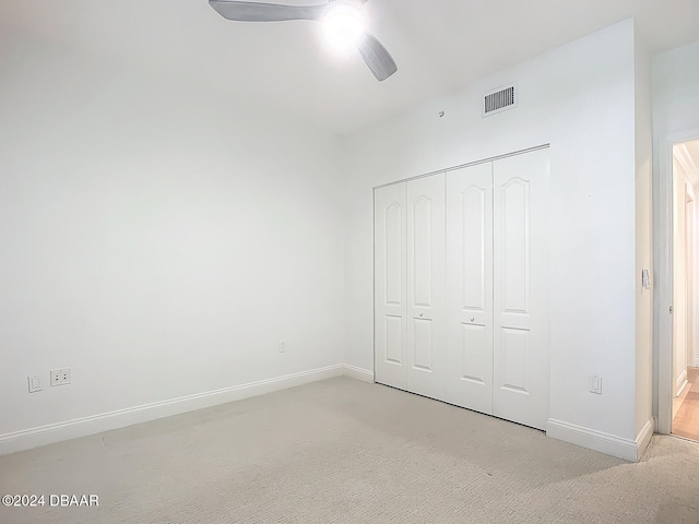 unfurnished bedroom with ceiling fan, light colored carpet, and a closet