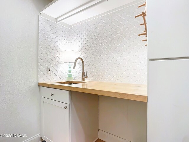 kitchen featuring appliances with stainless steel finishes, white cabinetry, decorative backsplash, hanging light fixtures, and light wood-type flooring