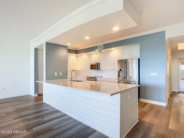 kitchen featuring sink, appliances with stainless steel finishes, light hardwood / wood-style floors, white cabinets, and decorative light fixtures