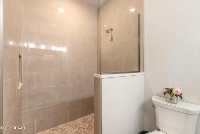 bathroom featuring toilet and tiled shower