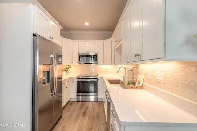 kitchen with white cabinets, sink, light wood-type flooring, and stainless steel appliances