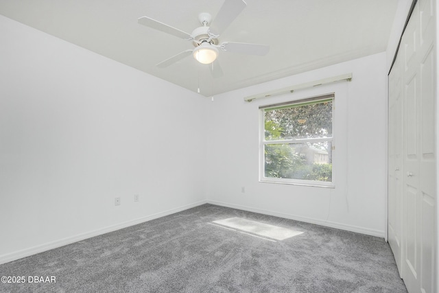 empty room featuring carpet flooring, a ceiling fan, and baseboards