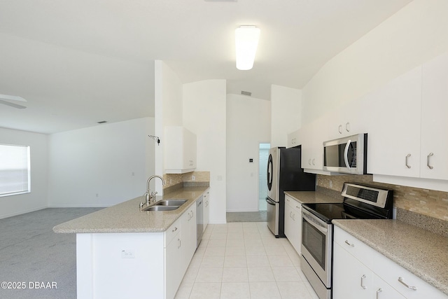 kitchen with a sink, stainless steel appliances, baseboards, a peninsula, and backsplash