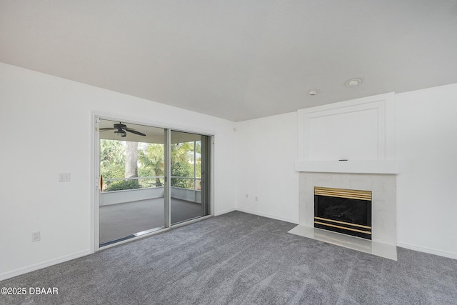 unfurnished living room featuring carpet floors, baseboards, ceiling fan, and a tiled fireplace