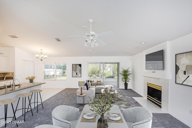 dining space with a premium fireplace, visible vents, plenty of natural light, and ceiling fan with notable chandelier