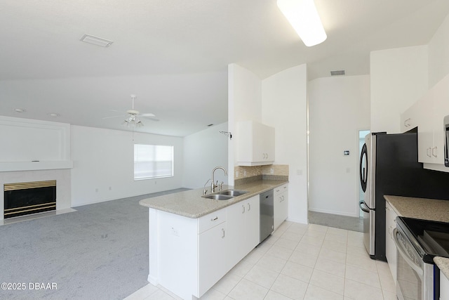 kitchen featuring a ceiling fan, appliances with stainless steel finishes, a sink, a peninsula, and white cabinetry