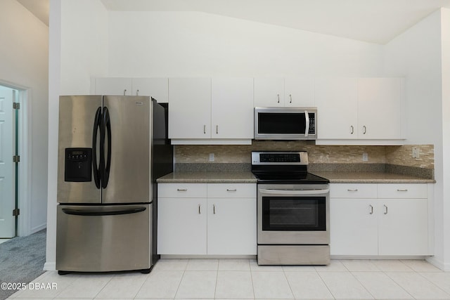 kitchen with dark countertops, appliances with stainless steel finishes, tasteful backsplash, and vaulted ceiling