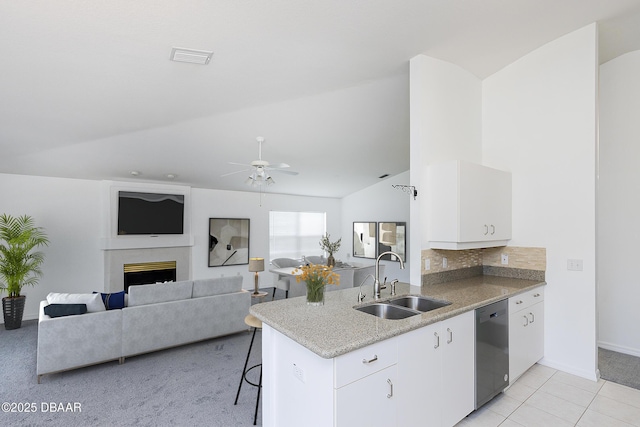 kitchen featuring ceiling fan, light stone counters, a sink, dishwasher, and vaulted ceiling
