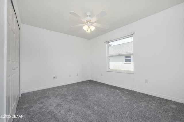 empty room featuring baseboards, ceiling fan, and dark colored carpet
