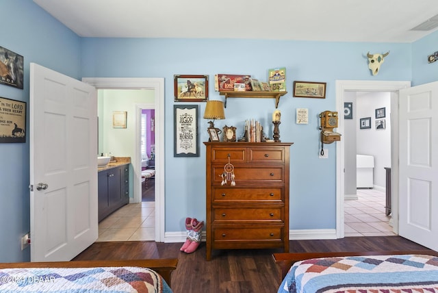 bedroom with a sink, baseboards, visible vents, and wood finished floors