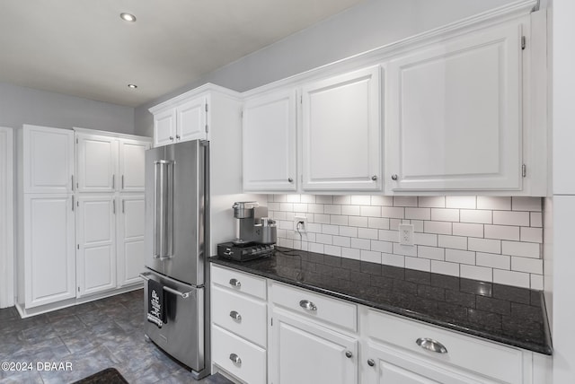 kitchen featuring dark stone countertops, high end refrigerator, white cabinets, and decorative backsplash