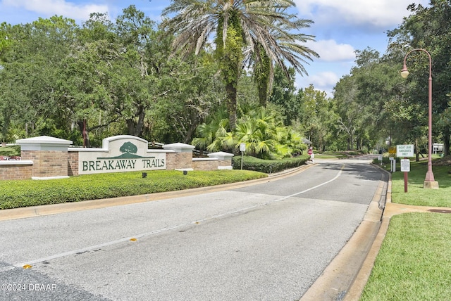 view of street with street lighting, traffic signs, a gated entry, and curbs