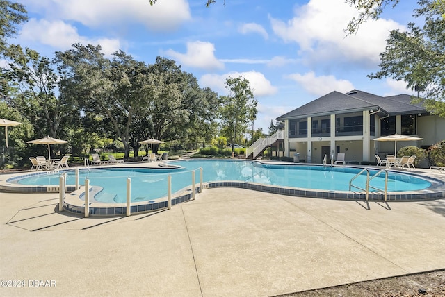 community pool with a patio area and stairs