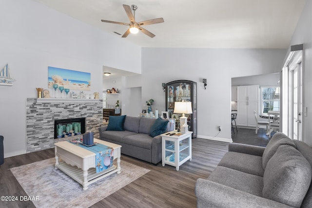 living area featuring ceiling fan, high vaulted ceiling, wood finished floors, baseboards, and a glass covered fireplace