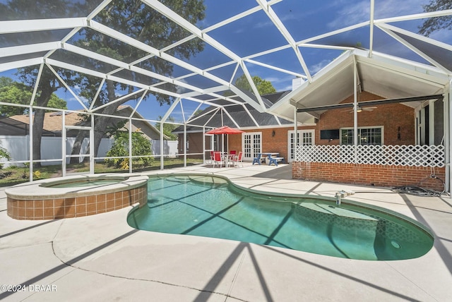 view of pool featuring a pool with connected hot tub, a patio area, ceiling fan, fence, and a lanai