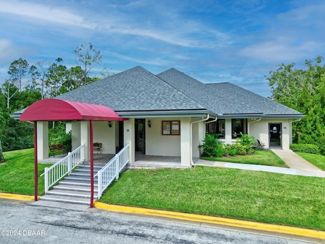 view of front of house featuring a shingled roof, a front yard, covered porch, and stucco siding