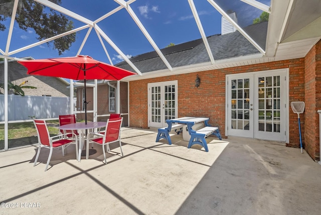 view of patio / terrace featuring glass enclosure, outdoor dining space, fence, and french doors