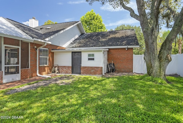 exterior space with a sunroom, a chimney, fence, a yard, and brick siding