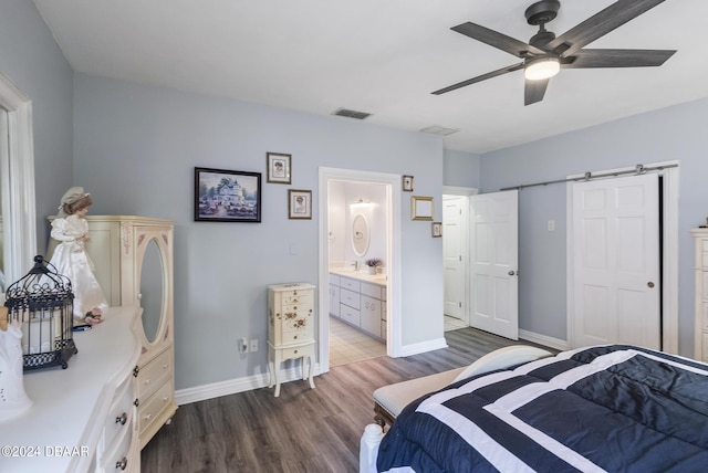 bedroom featuring a barn door, visible vents, baseboards, and dark wood-style flooring