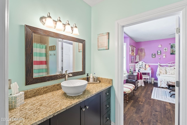 ensuite bathroom with baseboards, vanity, ensuite bath, and wood finished floors