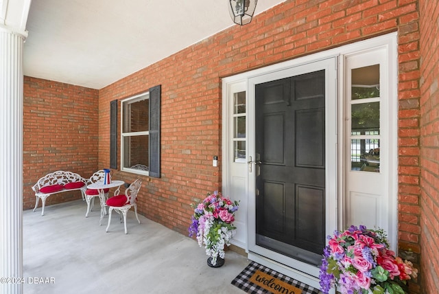 view of exterior entry featuring a porch and brick siding