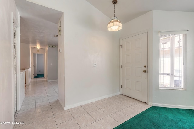 foyer featuring plenty of natural light, vaulted ceiling, and light tile patterned floors