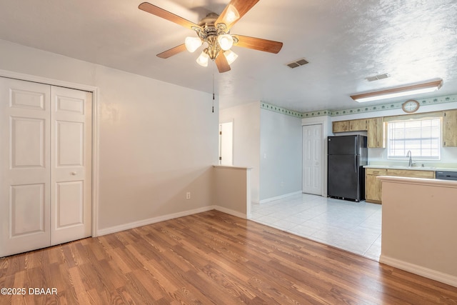 interior space featuring ceiling fan, sink, light hardwood / wood-style floors, and a textured ceiling