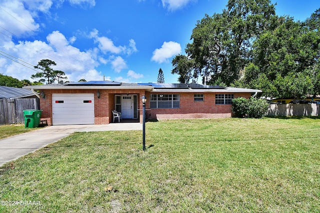 single story home featuring solar panels, a front yard, and a garage