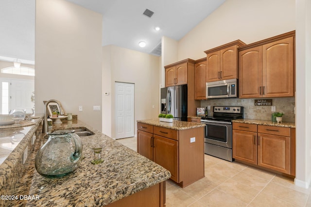 kitchen with light stone counters, kitchen peninsula, sink, and appliances with stainless steel finishes