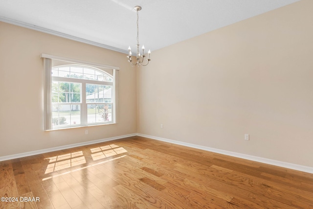 spare room with light hardwood / wood-style floors and an inviting chandelier