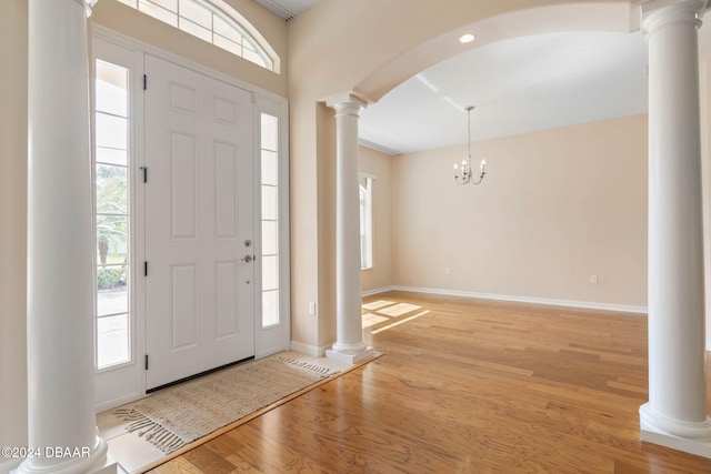 foyer entrance featuring light hardwood / wood-style flooring, a wealth of natural light, and a notable chandelier