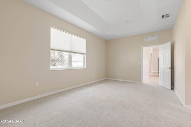 carpeted empty room with a raised ceiling