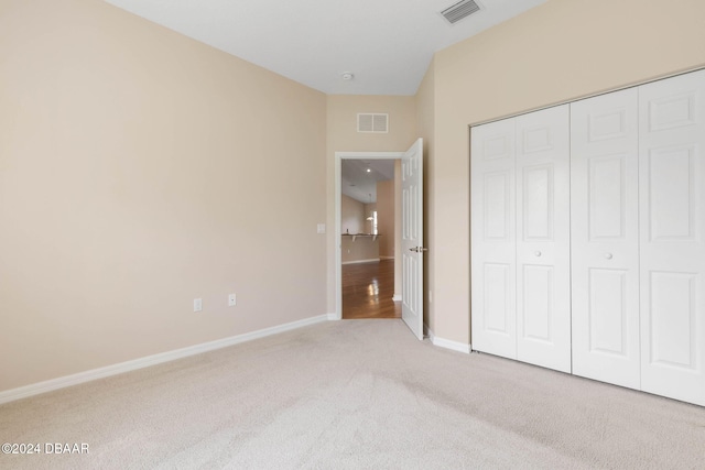 unfurnished bedroom with light carpet and a closet