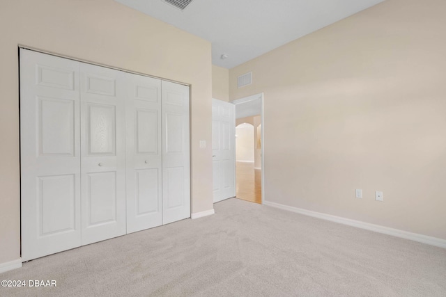 unfurnished bedroom featuring light colored carpet and a closet